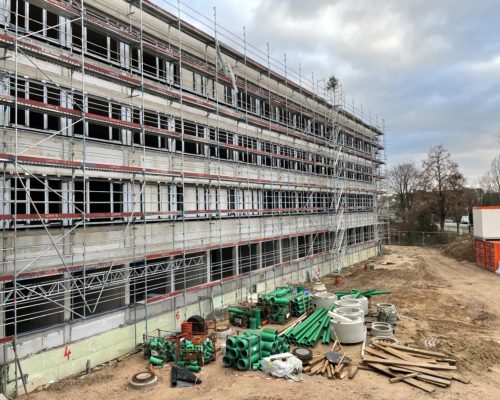 Baustellenbild. Es ist die Außenseite des neuen Schulgebäudes zu sehen.